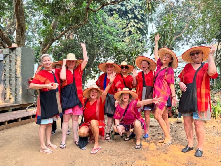 Lachende reisgroep in rode gewaden en strohoeden op een zandpad in de jungle