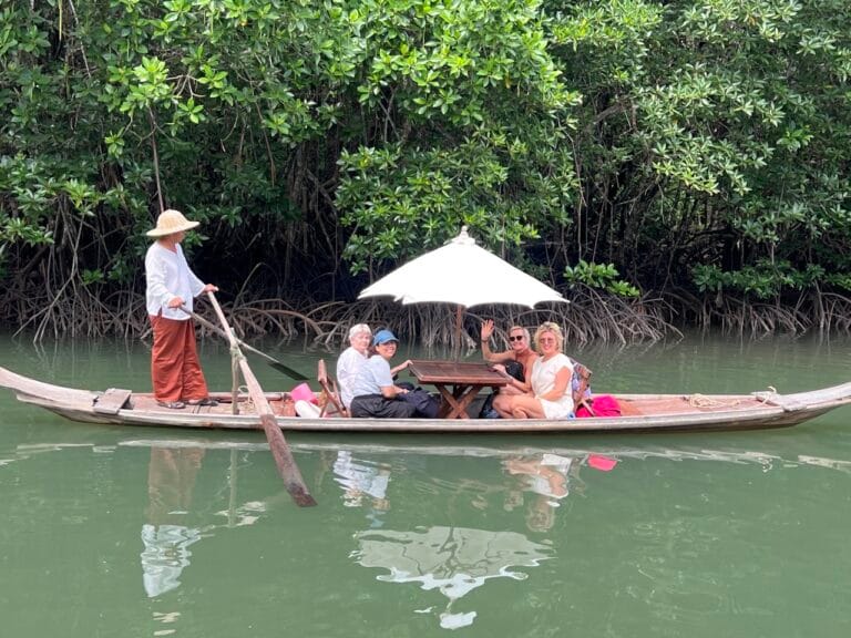 Reizigers in een houten boot door het mangrovebos